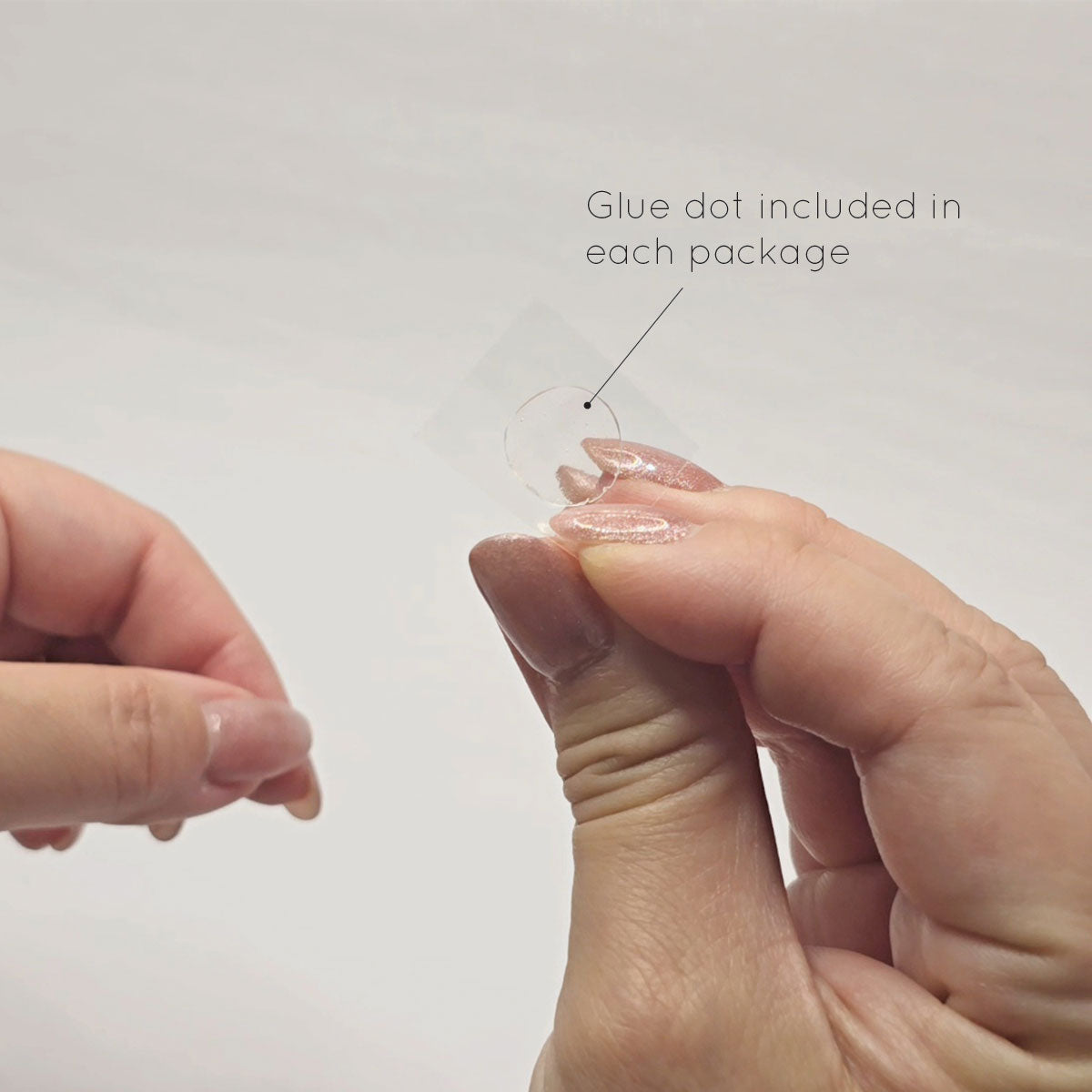 Hand holding the glue dot.